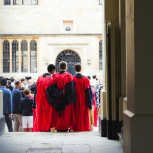 Faceless men in red cloaks standing on crowded square