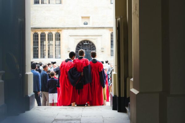 Faceless men in red cloaks standing on crowded square